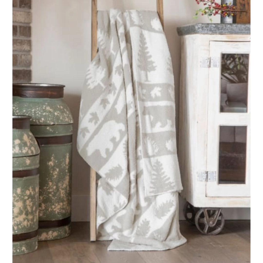 White patterned blanket draped over a wooden frame with decorative vases and a cabinet in the background.