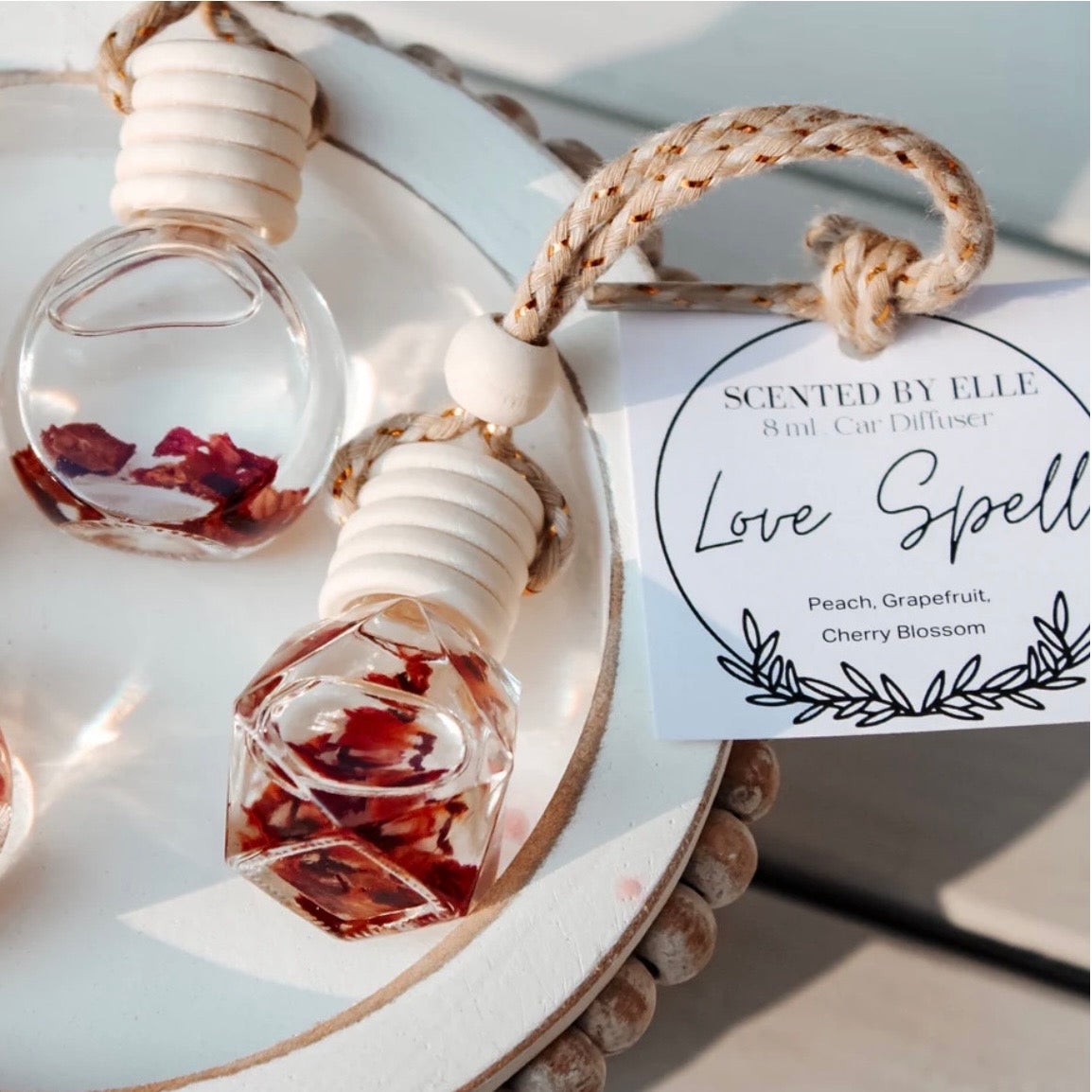 Car diffuser with natural elements and 'Love Spell' label on a light background