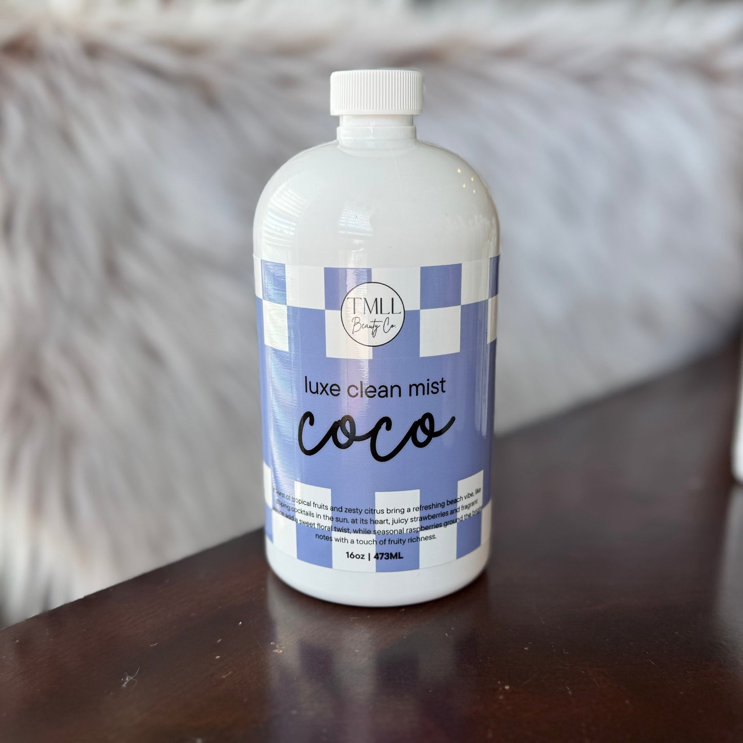 Bottle of 'Coco' luxe clean mist on a wooden surface with a blurred background
