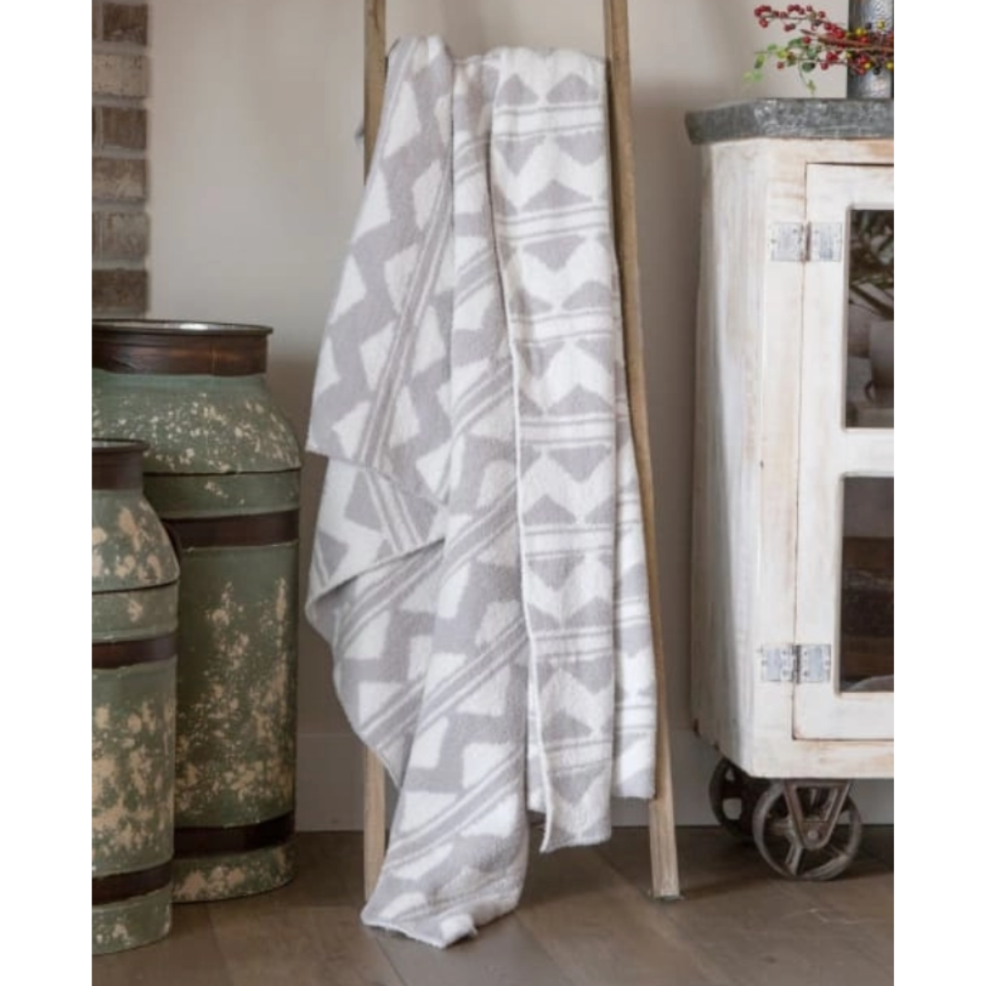 Gray patterned towel draped over a wooden stand with decorative vases and a cabinet in the background.