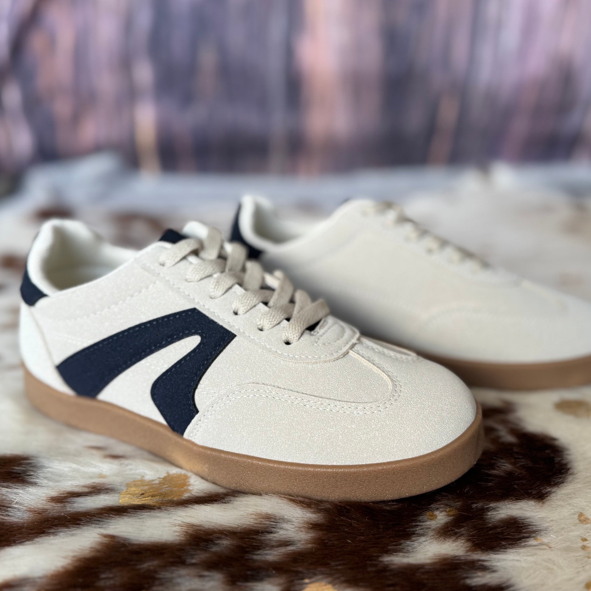 White sneakers with navy swoosh logo on a patterned surface