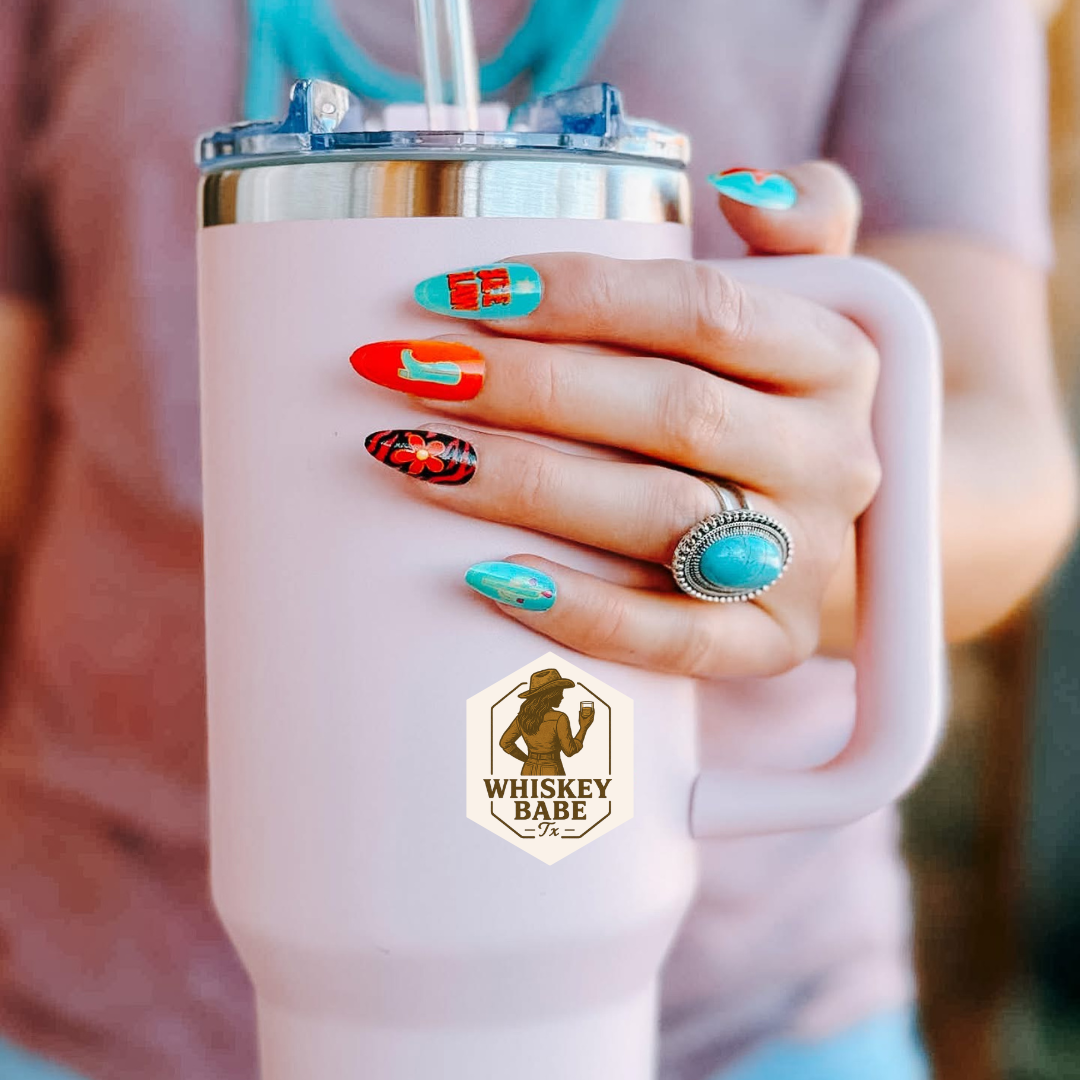 Person holding a pink tumbler with colorful western element nails 