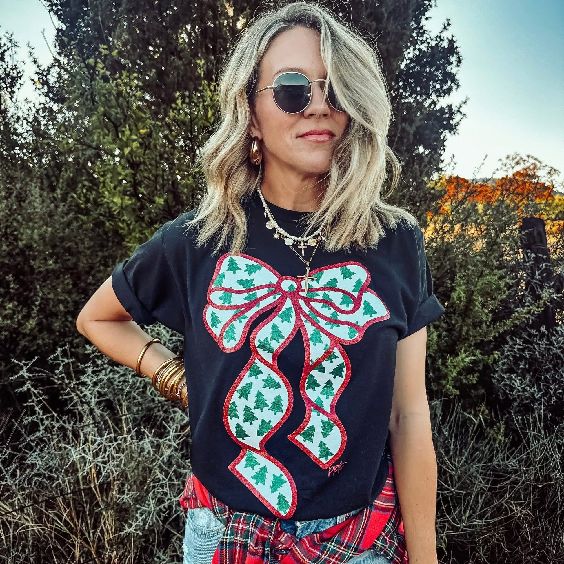 Woman wearing a black t-shirt with a large green bow design outdoors.