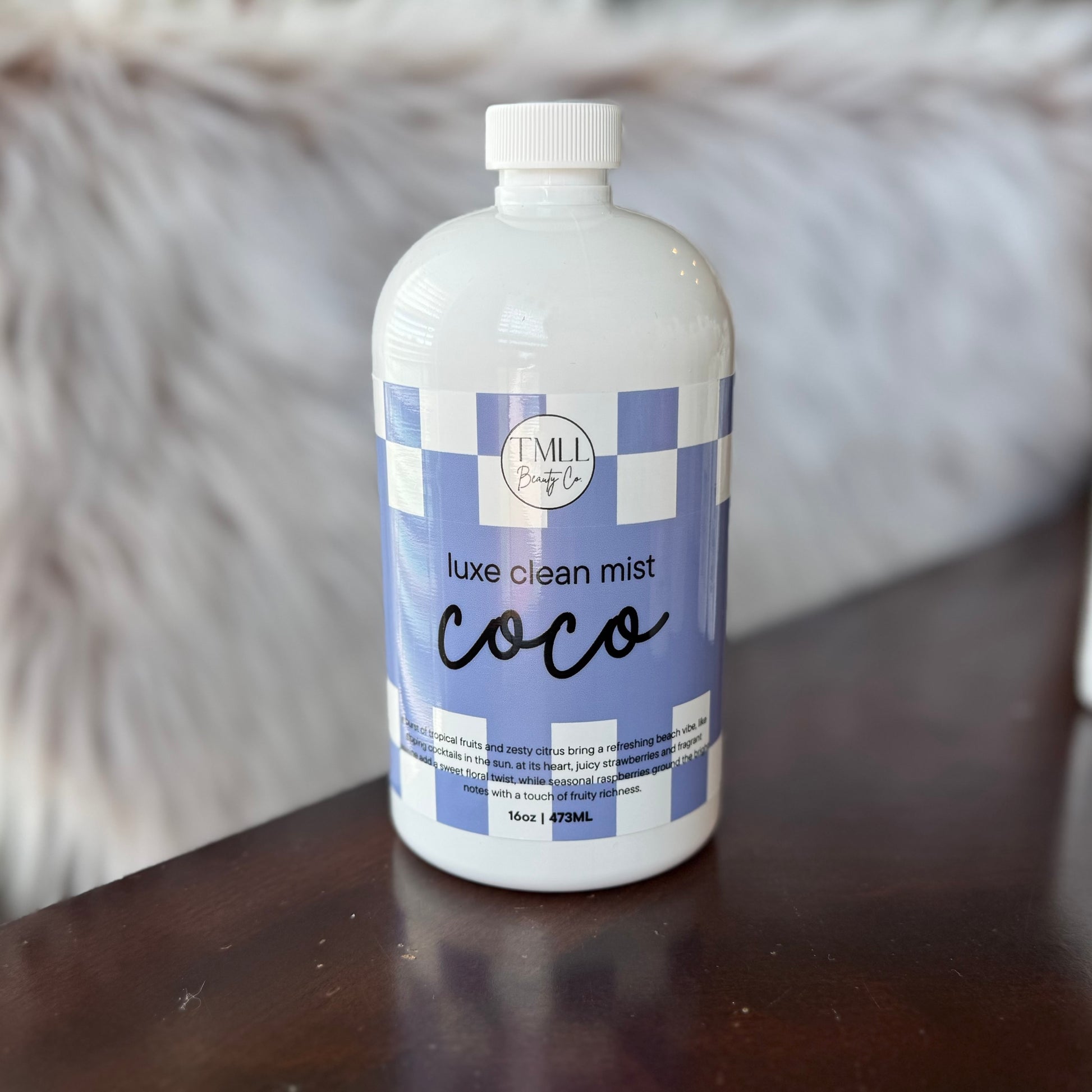 Bottle of 'Coco' luxe clean mist on a wooden surface with a blurred background
