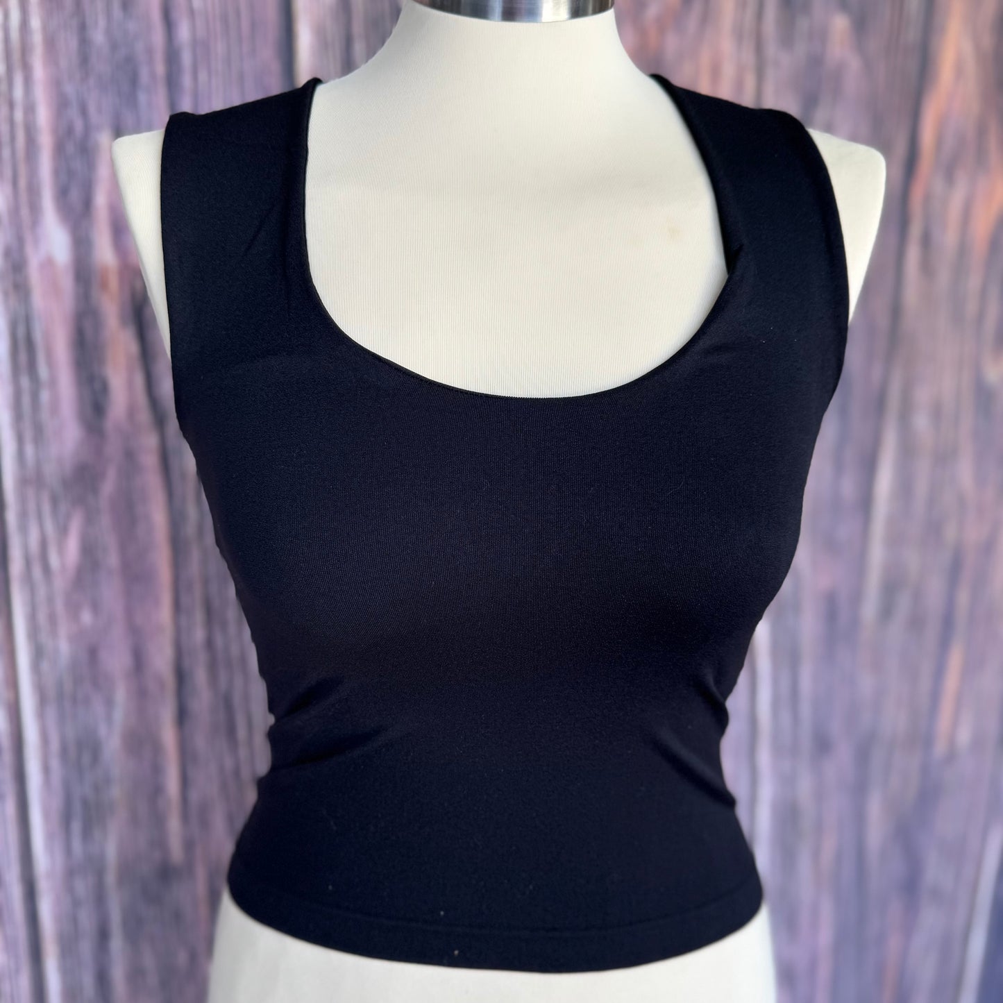 Black tank top on a mannequin against a wooden background