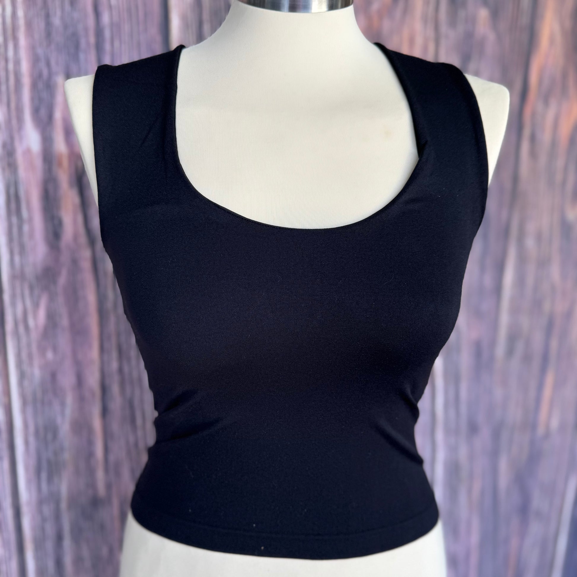 Black tank top on a mannequin against a wooden background