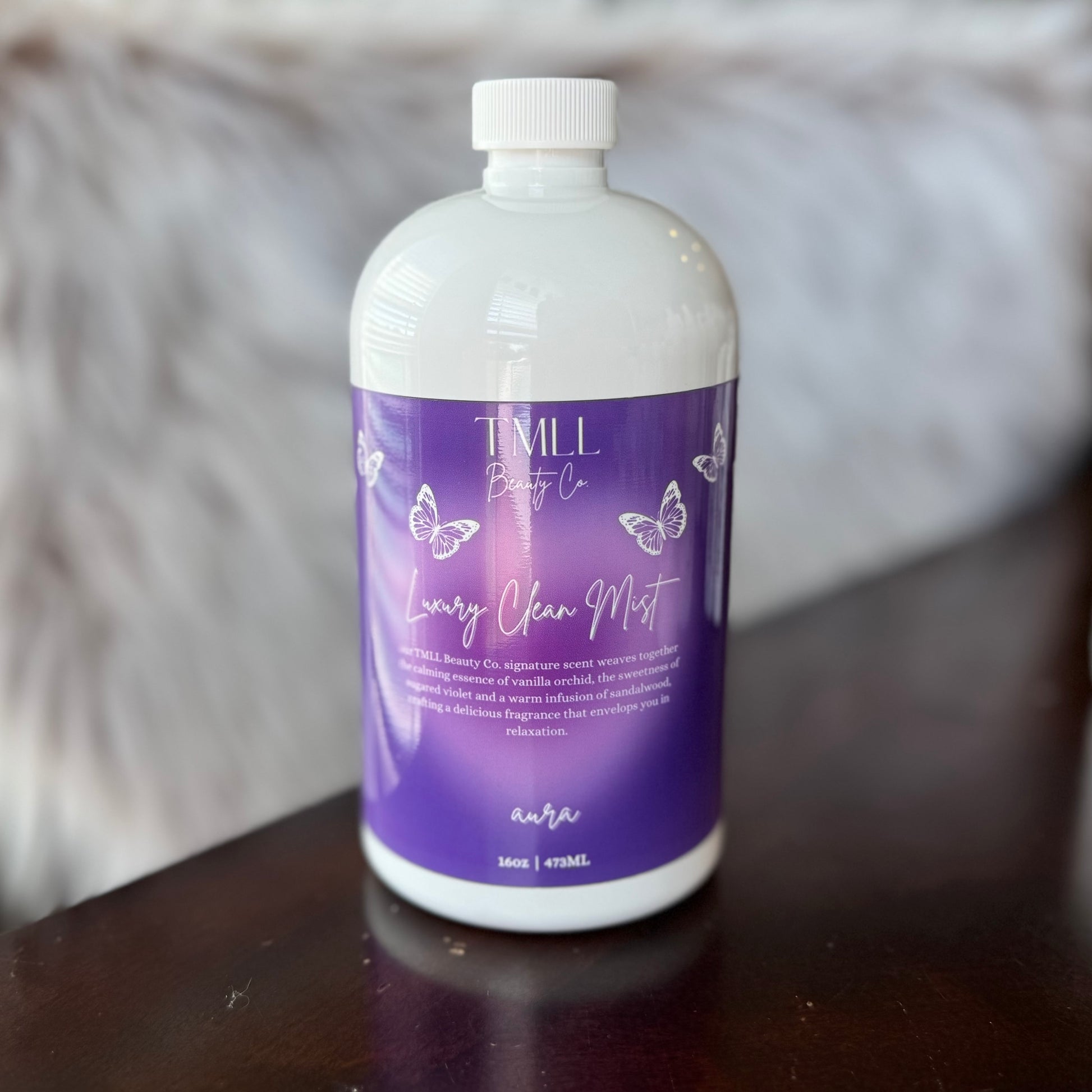 Bottle of Aura Clean Mist on a wooden surface with a blurred background