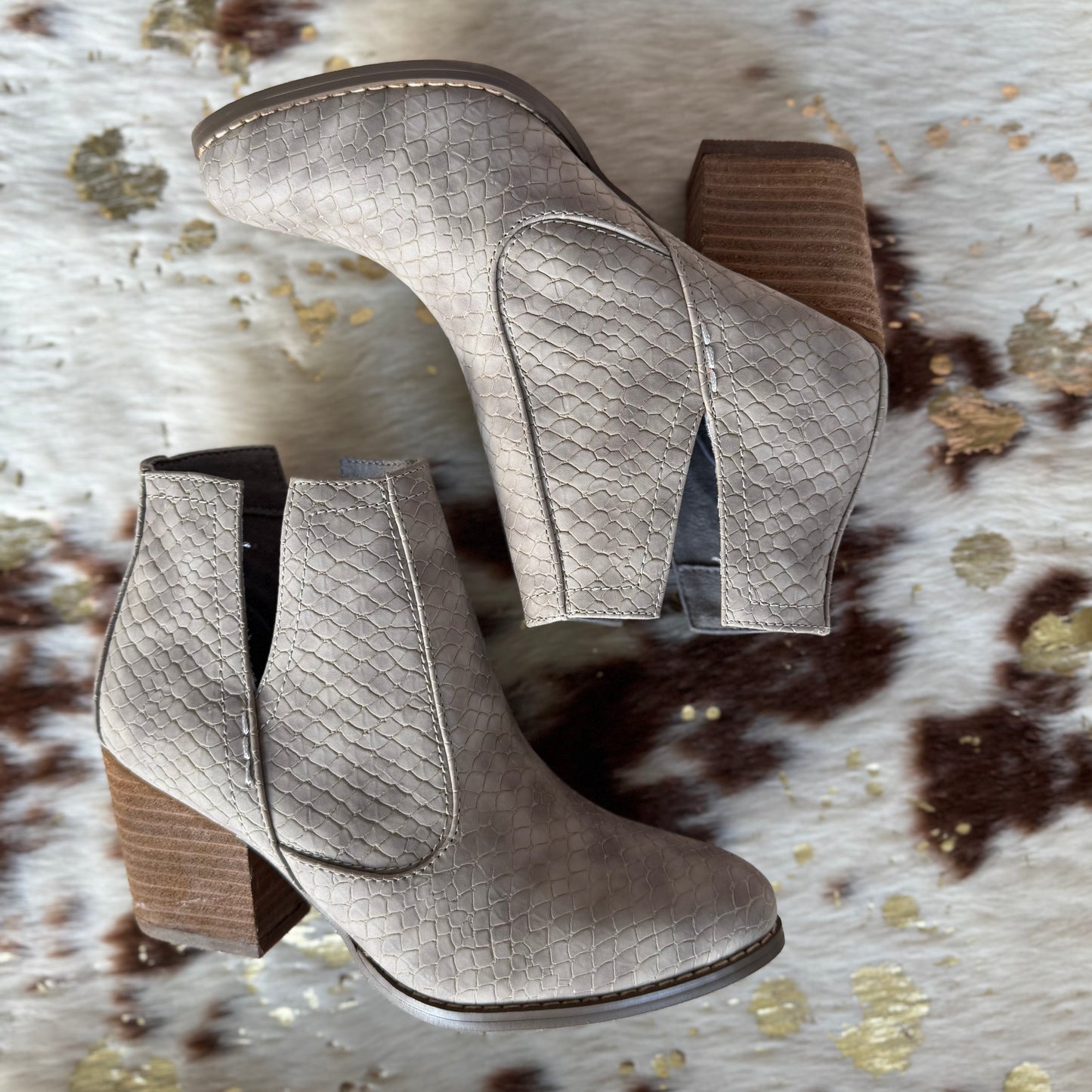 Pair of gray suede ankle boots with a textured pattern on a patterned surface.