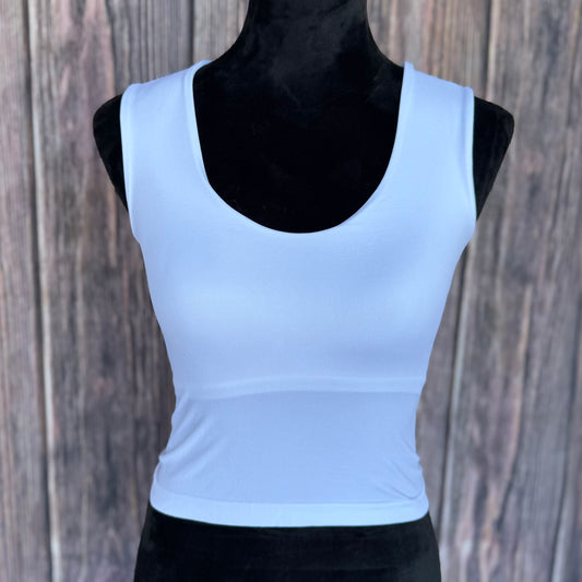 White tank top on a black mannequin against a wooden background