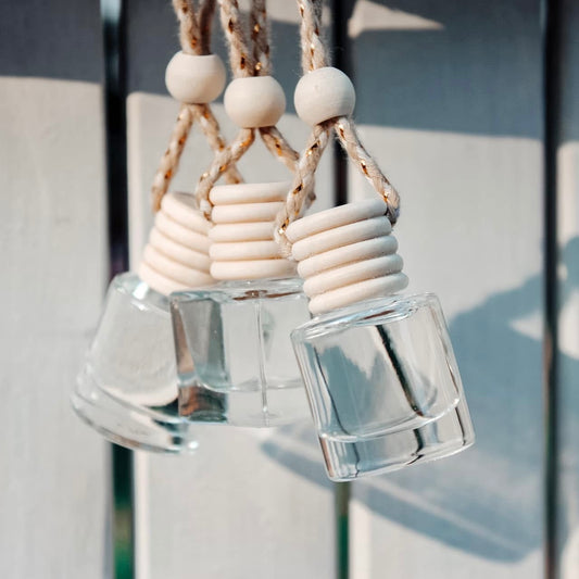 Clear glass bottles with wooden beads hanging against a neutral background