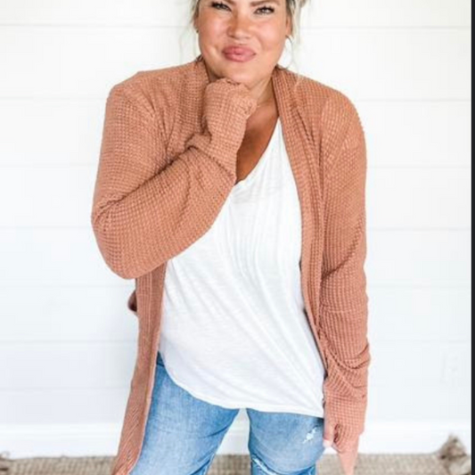 Woman wearing waffle knit cardigan sweater in a clay color.